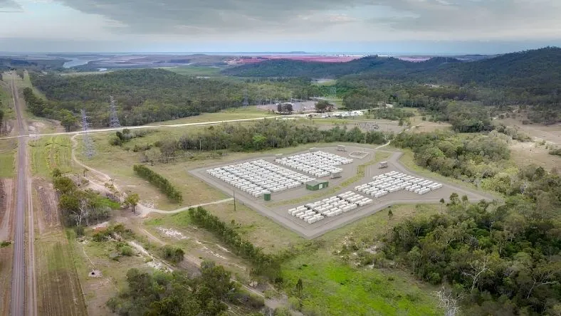 Aerial view of white BESS units in a cleared rural site surrounded by native trees