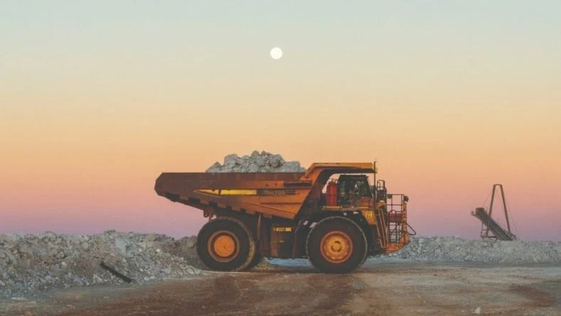 Diesel haul truck carrying ore under a full moon at dusk